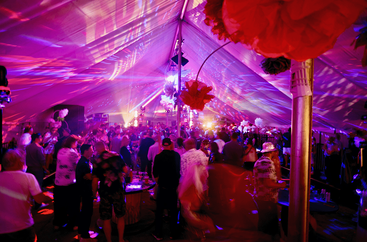 Festivalgoers dancing at Campo Sancho with colourful lights and countryside backdrop at Walkern Hall